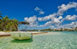 a boat sitting in the water on a beach at Charmant Studio Vue Mer Village Soleil in Le Gosier