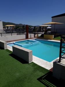 een groot blauw zwembad met groen gras naast een gebouw bij Departamento in Villa Carlos Paz