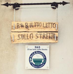ein Schild, das an einer Wand hängt, mit einem Straßenschild. in der Unterkunft Il Tuo Letto Sullo Stretto in Reggio di Calabria