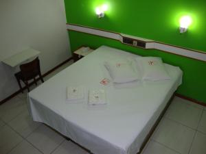 a bedroom with a white bed with green walls at Hotel - Pousada do Arco Iris in Osasco