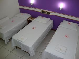 3 camas en una habitación con paredes moradas en Hotel - Pousada do Arco Iris en Osasco