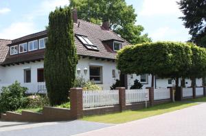 ein weißes Haus mit einem Zaun und Bäumen in der Unterkunft Ferienwohnung im Auetal - Wohnung I in Hanstedt