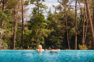 two people swimming in a pool with trees in the background at Mobile Homes Camping Santa Marina, Lanterna in Poreč