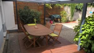 une table et des chaises en bois assises sur une terrasse dans l'établissement Gîte Studio Tarbes Pyrénées, à Tarbes