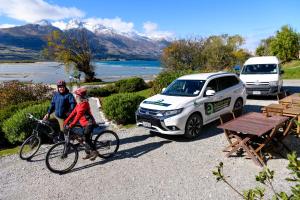 a person riding a bike next to a car at Kinloch Wilderness Retreat in Glenorchy