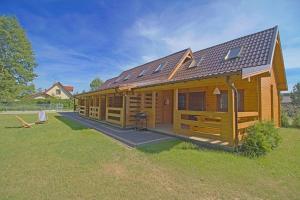 a large wooden cabin with a grassy yard at Domki na 102 in Junoszyno