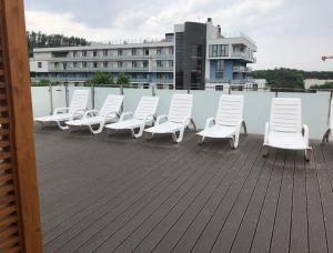 Una fila de sillas blancas sobre un tejado. en Apartament Bliżej Morza, en Kołobrzeg