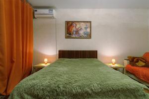 a bedroom with a green bed and two tables with candles at Apartment On Perevertkina 24а in Voronezh