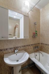 a bathroom with a sink and a mirror and a tub at Apartment On Perevertkina 24а in Voronezh