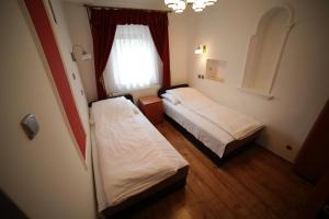 2 camas en una habitación pequeña con ventana en Eged Vendégház, en Eger
