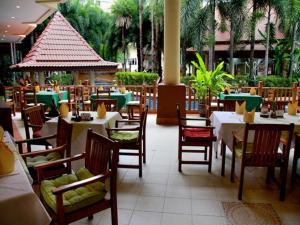 Baumanburi Hotel - SHA Extra Plus في شاطيء باتونغ: مطعم بطاولات بيضاء وكراسي