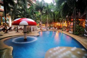 uma piscina com um guarda-sol vermelho num resort em Baumanburi Hotel - SHA Extra Plus em Patong Beach