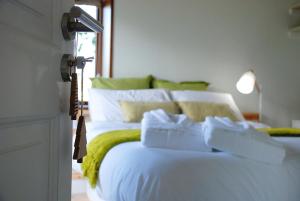 a white bed with white pillows and a green blanket at Cal Baridà in Cava