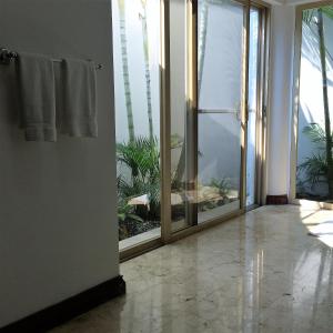 une porte ouverte menant à une salle de bains avec des portes coulissantes en verre. dans l'établissement Hotel Boutique Villa Casuarinas, à Cali