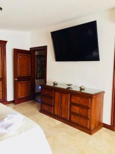 - une chambre avec un lit et une télévision murale à écran plat dans l'établissement Hotel Boutique Villa Casuarinas, à Cali