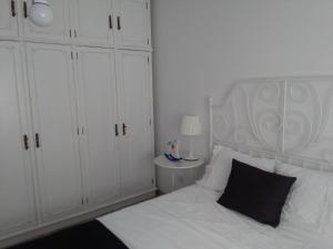 een slaapkamer met een wit bed en een zwart kussen bij Jardim à vista in Aveiro