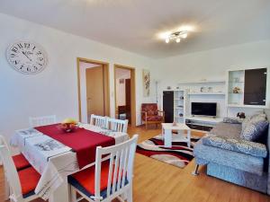 a living room with a table and a clock on the wall at Apartmani Roza Lopar in Lopar