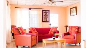 The Jam Lodge في فريتاون: غرفة معيشة مع أريكة حمراء وكراسي