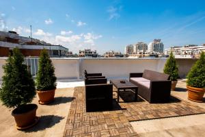 a rooftop patio with chairs and a table and potted trees at Arena Penthouse Apartments in Belgrade
