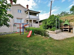 a yard with a playground in front of a house at Apartmani Roza Lopar in Lopar