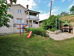 a yard with a playground in front of a house at Apartmani Roza Lopar in Lopar