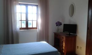 a bedroom with a bed and a television and a window at Monte da Cardela Nova in Melides