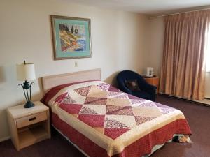 a hotel room with a bed with a quilt on it at Slumber Lodge Williams Lake in Williams Lake