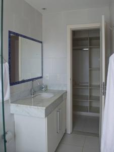 Baño blanco con lavabo y espejo en Apartamento Centro Búzios, en Búzios