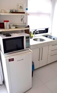 eine Küche mit Mikrowelle und Spüle in der Unterkunft Apartamento Centro Búzios in Búzios