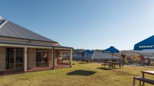 ein Gebäude mit Picknicktischen und blauen Sonnenschirmen in der Unterkunft Bowen Inn Motel in Lithgow