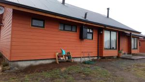 una casa roja con una silla delante en Hostal Parcela 47 villarrica, en Villarrica