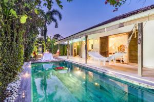 an outdoor swimming pool with a hammock next to a house at Villa 007 in Seminyak