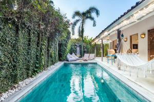 a swimming pool with chairs and a house at Villa 007 in Seminyak