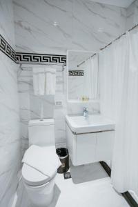 Baño blanco con aseo y lavamanos en PVL Suites, en Dumaguete