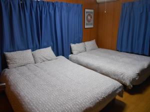船橋市にあるファミリー リゾート アパートメントの青いカーテンが備わる客室のベッド2台