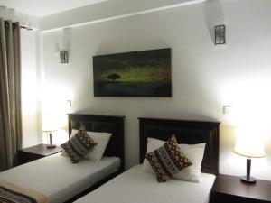 two beds in a room with two lamps and a painting at Twin Villa 22 in Katugastota