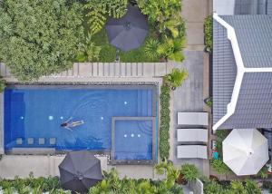 an overhead view of a swimming pool with two umbrellas at Mudita Villa Siem Reap in Siem Reap