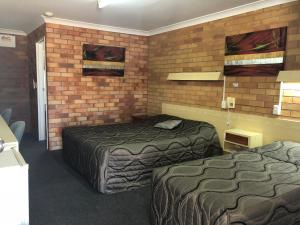 a hotel room with two beds and a brick wall at Glen Innes Lodge Motel in Glen Innes