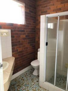 a bathroom with a toilet and a glass shower at Glen Innes Lodge Motel in Glen Innes