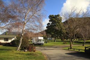 a white truck parked in a park with trees at Parklands Marina Holiday Park in Picton