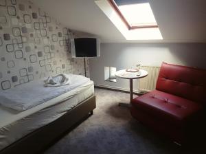 a bedroom with a bed and a red chair and a table at Pension Klabautermann in Stralsund