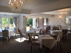a dining room with tables and chairs and a chandelier at Farnham House Hotel in Farnham