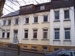 Un grand bâtiment blanc avec de nombreuses fenêtres donne sur une rue. dans l'établissement Zimmervermietung Hartl, à Barmstedt