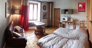 a bedroom with a bed and a couch and a table at Au Coeur du Lapidaire in Septmoncel