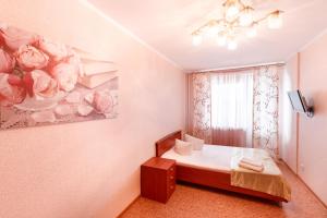 トムスクにあるКвартира на Большой Подгорнойのベッドルーム1室(ベッド1台付)が備わります。壁には絵画が飾られています。