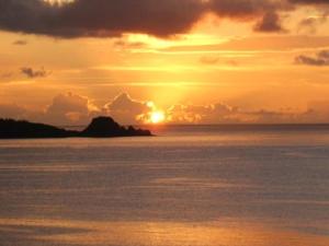 um pôr do sol sobre um corpo de água com o pôr do sol em Auberge Bonne Chere Raout em Onna