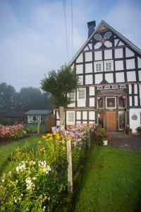 czarno-biały dom z kwiatami na dziedzińcu w obiekcie Pension Alois Hennecke w mieście Schmallenberg