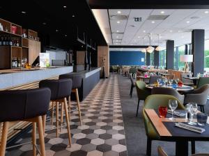 a restaurant with a bar and tables and chairs at Novotel Caen Côte de Nacre in Caen