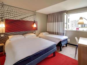um quarto de hotel com duas camas e uma janela em ibis Orleans Centre Gare em Orléans