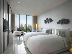 a hotel room with a large bed and a large window at SO BANGKOK - SHA Extra Plus in Bangkok